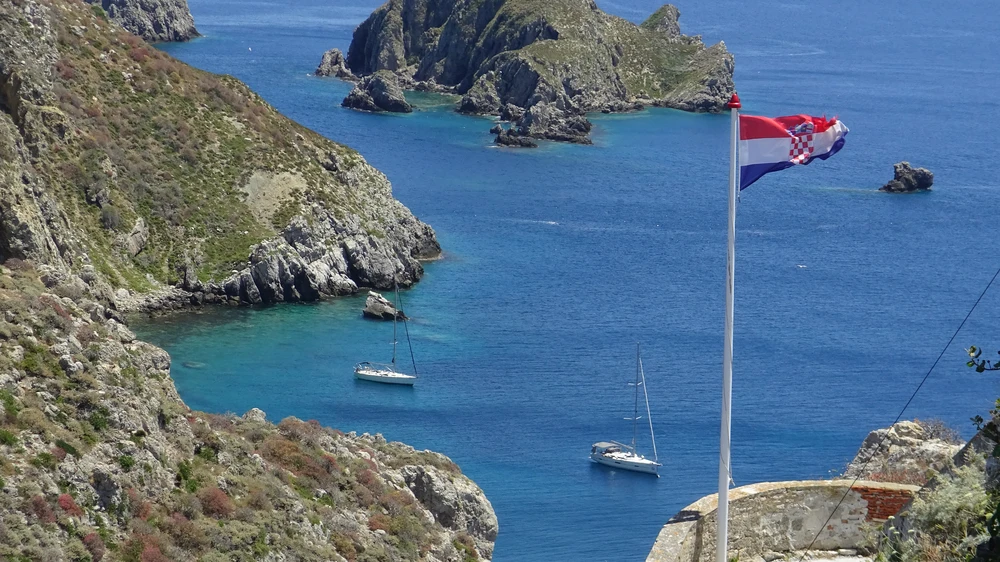 Die Flagge und im Hintergrund unsere Yacht vor Anker.